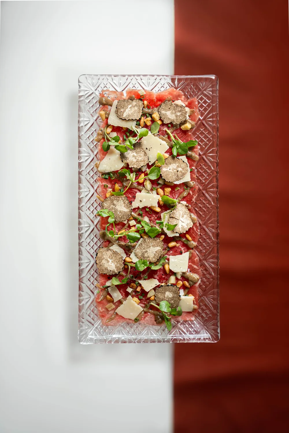 Carpaccio de bœuf à la truffe noire et copeaux de parmesan sur plat en verre taillé