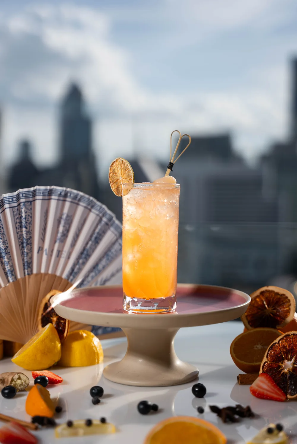 Cocktail long drink glacé garni d'un citron séché, éventail Pastel en décor