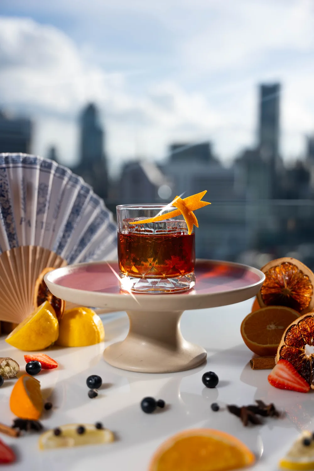 Cocktail Negroni servi sur un présentoir, skyline de Bangkok en arrière-plan