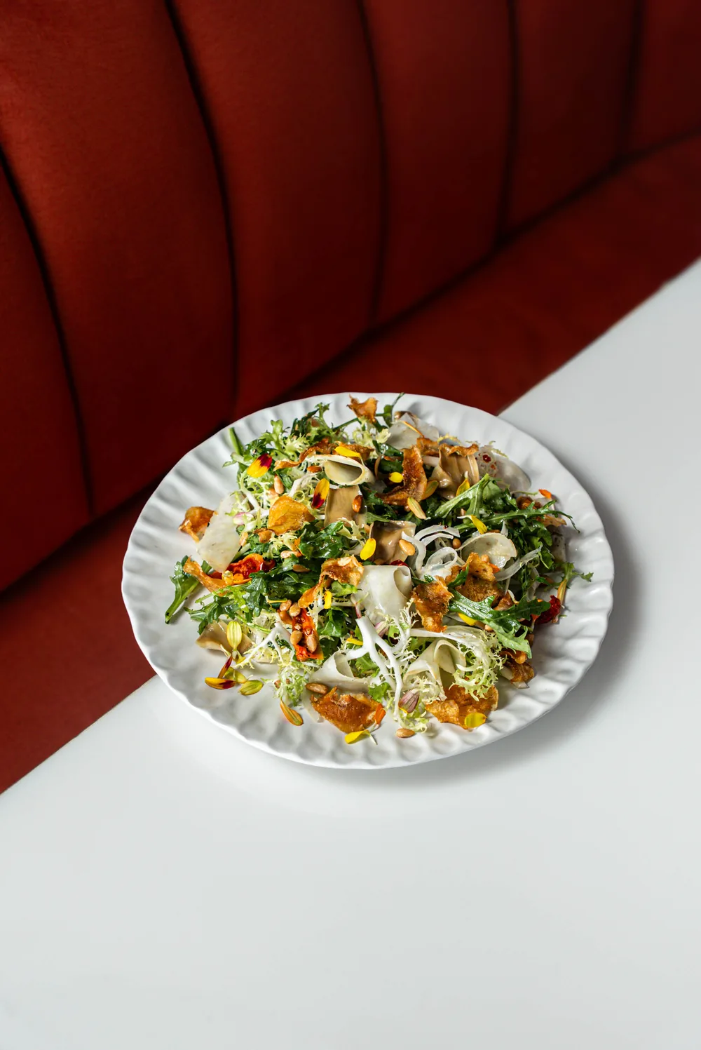 Salade de jeunes pousses, pleurotes et fleurs comestibles sur assiette blanche