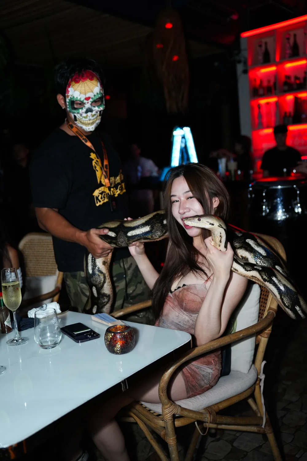 Invitée faisant mine de mordre un python pendant un show animalier au Pastel à Bangkok