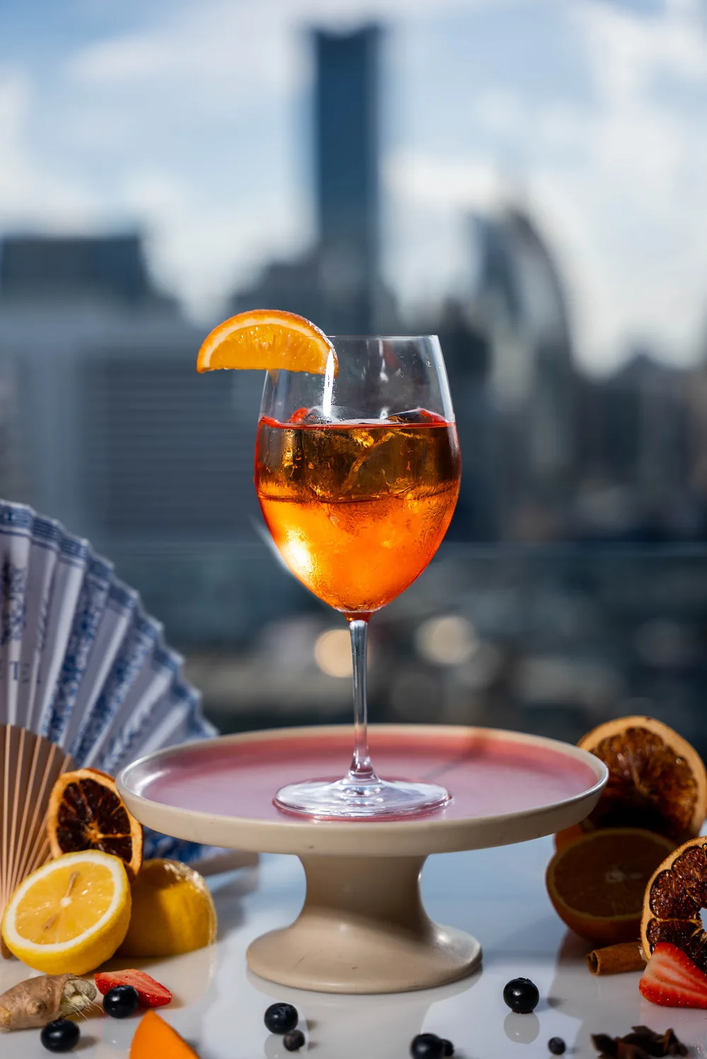 Spritz à l'orange sur un rooftop de Bangkok, gratte-ciel en fond flou